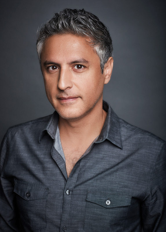 A man in a gray dress shirt with short hair looking at the camera.