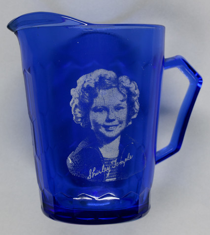 A blue creamer featuring child star Shirley Temple’s face and signature in white.