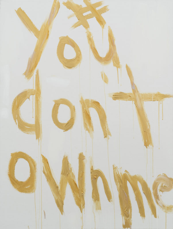 A painting of the words #Youdon'townme in yellow paint on a white canvas.