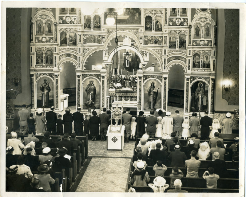 Wide shot of church patrons sitting in pews.