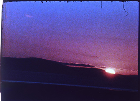 Pink and blue sunset with the sun just visible over the dark horizon in the bottom right corner.