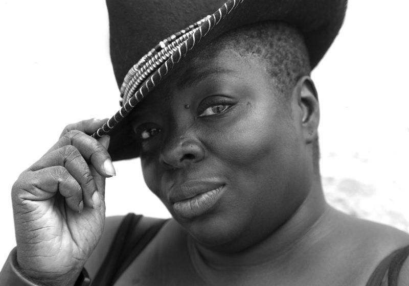 Black and white image of a person tipping their hat towards the front.