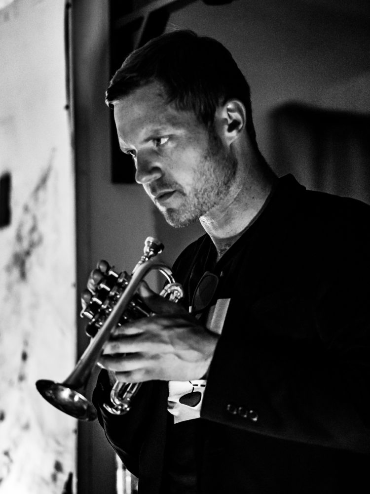 Black and white photograph of a man playing a horn instrument.