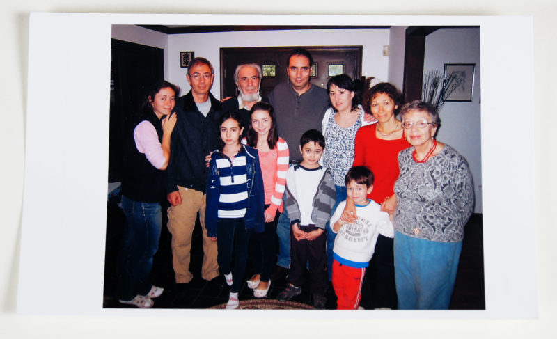 Color photograph of a multi-generational family. There are four children in the photo and seven adults of various ages.