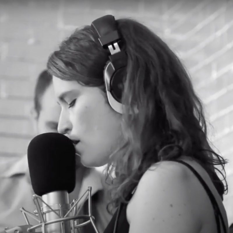 Woman wearing headphones singing into a microphone