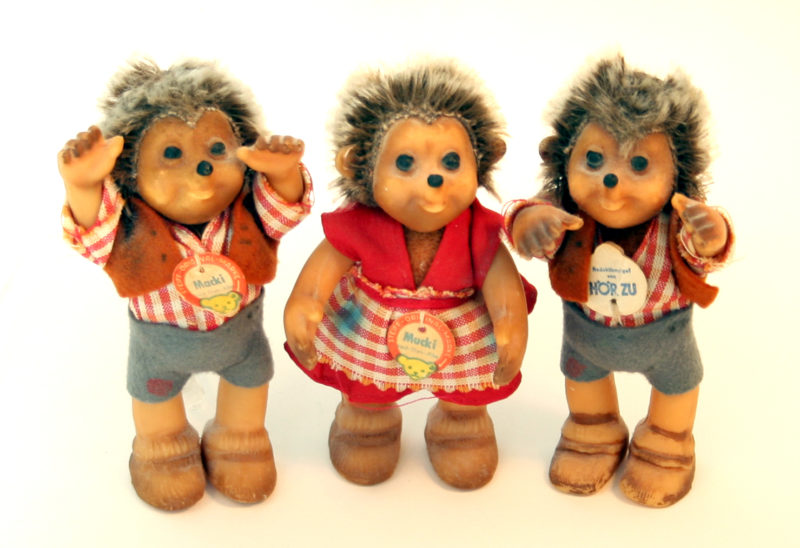 A female child hedgehog figurine stands between two male children hedgehog figurines.