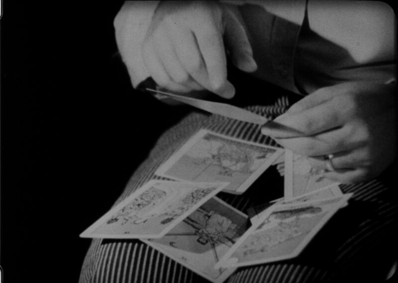 Black and white film still of a close up of tarot cards on a person's lap.