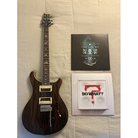 A black, electric guitar with two record albums sitting beside it