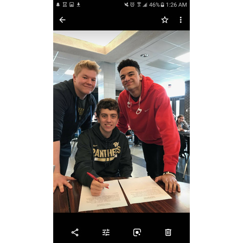 Photo of a man sitting at a desk with two people on either side