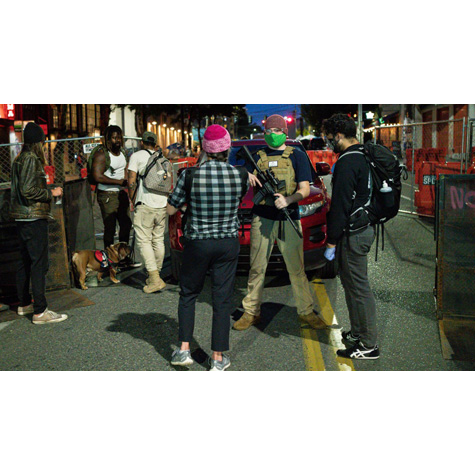 A group of young people standing around a man holding a gun during a protest