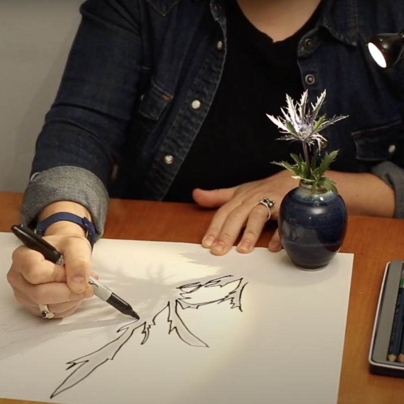 A woman outlines a shadow using a black marker.